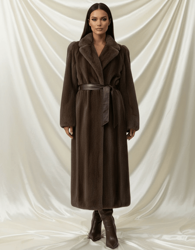 Woman wearing a brown coat and boots against a white draped curtain background